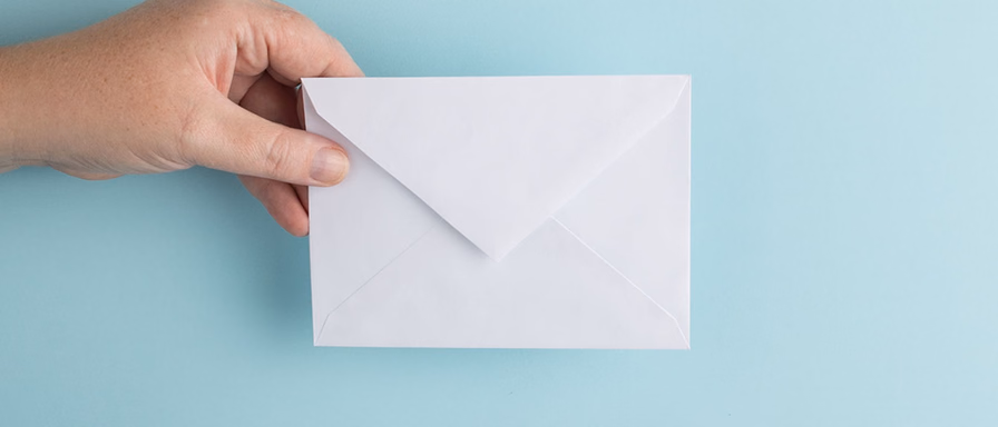 A hand holding a mail envelope.